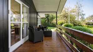 Un espace extérieur abrité, aménagé avec des meubles en osier et une terrasse en bois.