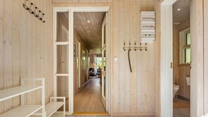 Un intérieur en bois avec un couloir menant à une salle à manger, une étagère blanche et des prises électriques au mur.