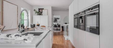 Una cocina moderna con armarios blancos, una isla central y un horno empotrado.