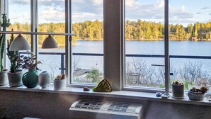 A room with a large window overlooking a lake and forest. - Cozy home in Värmdö with sauna (Värmdö)