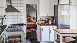 A compact kitchen with white cabinets, a stainless steel sink, and a refrigerator. - Cozy home in Värmdö with sauna (Värmdö)