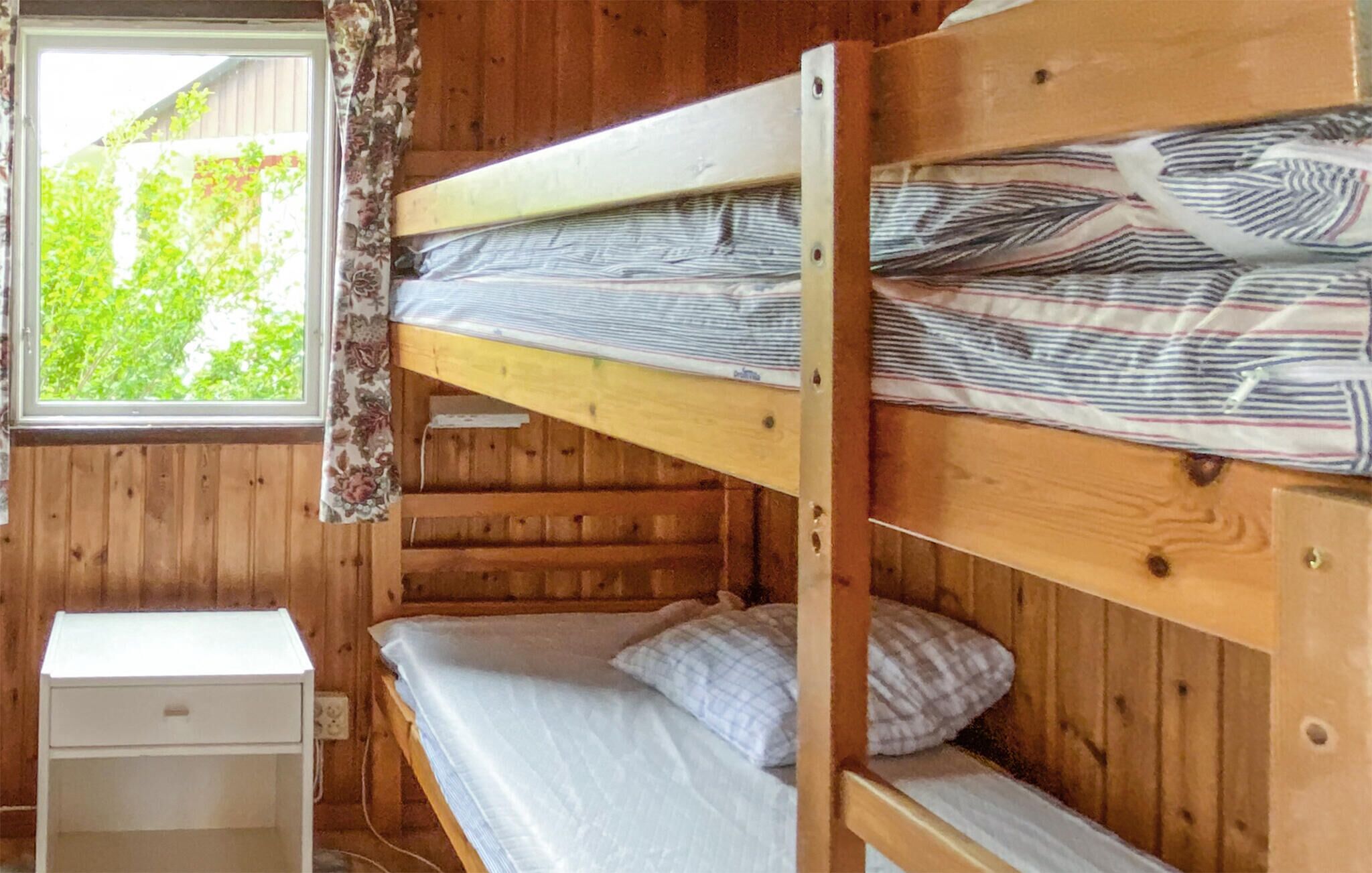Habitación con literas, una mesita de noche pequeña y vistas al exterior a zonas verdes.