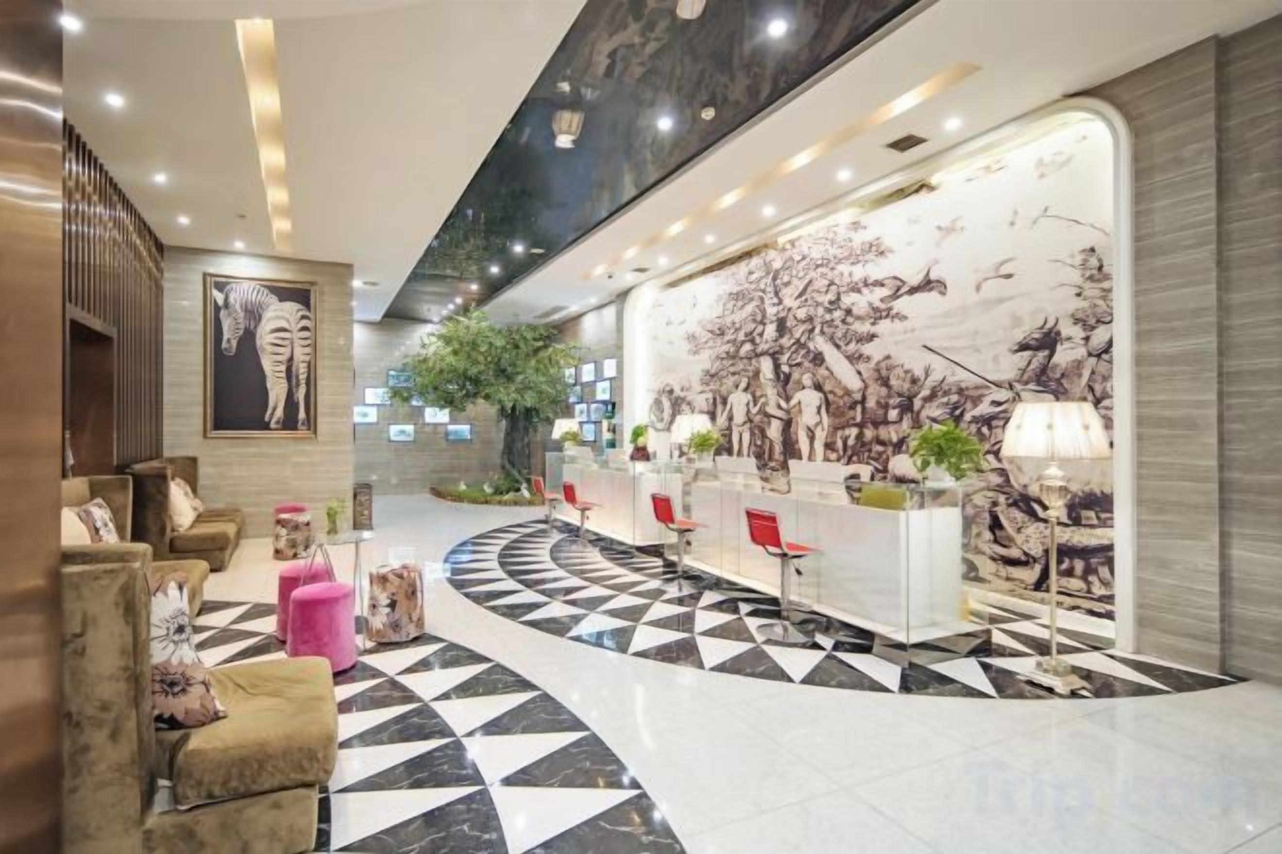 A hotel lobby with a check-in counter, seating area, and a large mural.