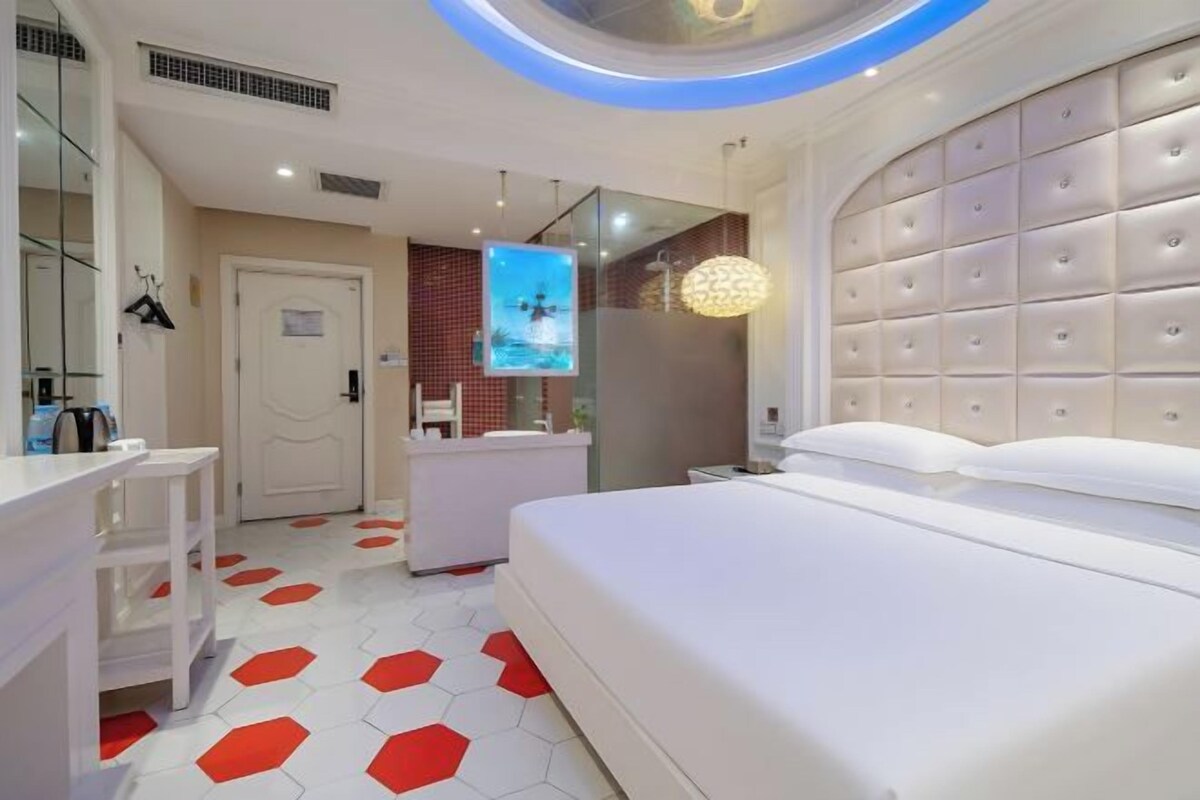 Una habitación de hotel moderna con una cama grande, un tocador con espejo, un escritorio pequeño y un piso con un patrón hexagonal único.