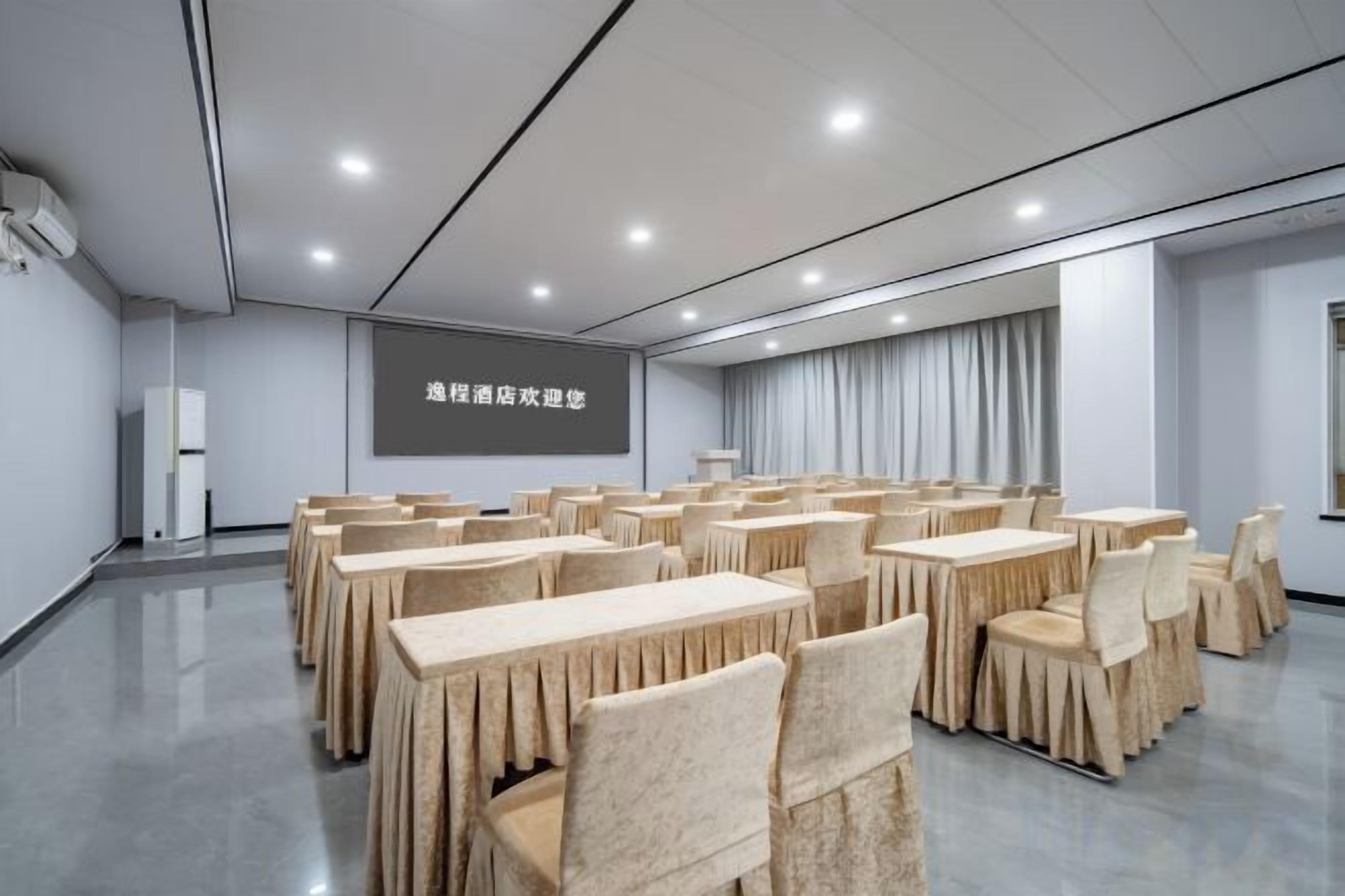 A conference room with tables and chairs, a projector screen, and a presentation screen.