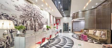 Un vestíbulo de hotel con mostrador de recepción, zona de estar y un gran mural.