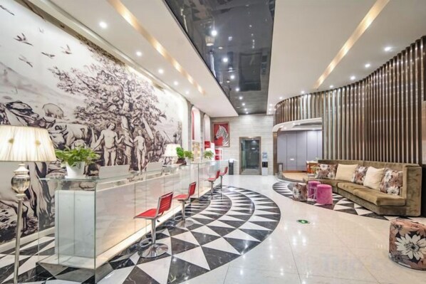 Un vestíbulo de hotel con mostrador de recepción, zona de estar y un gran mural.