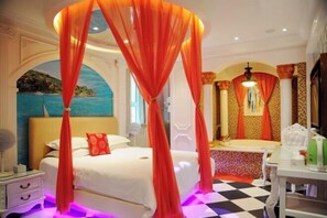 Ein Schlafzimmer mit Himmelbett, einem großen Spiegel, einem Waschbecken und einem Schminktisch.