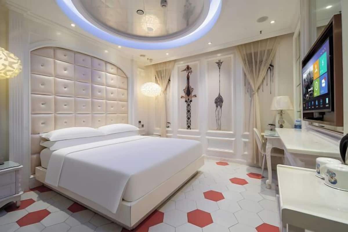 Een moderne hotelkamer met een groot bed, een bureau en een televisie.