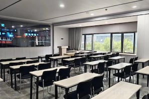 Ein Klassenzimmer mit mehreren Tischen und Stühlen, großen Fenstern und Blick ins Freie.