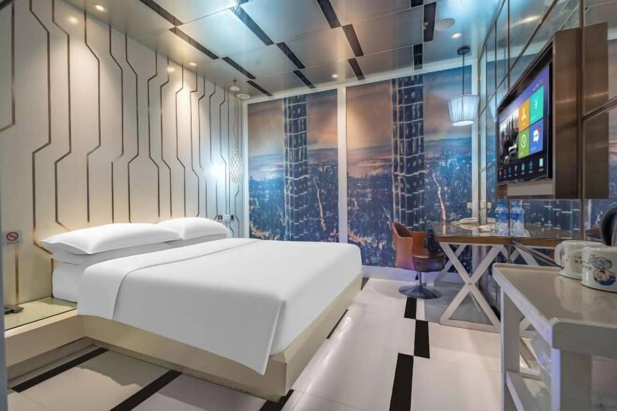 Een moderne hotelkamer met een bed, een bureau en uitzicht op de stad.