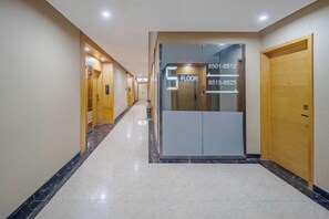A hotel corridor with a marble floor, wooden doors, and an elevator with floor numbers. - Yi Cheng Hotel (Xinbai Square Subway Station Store, Shijiazhuang) (Shijiazhuang)