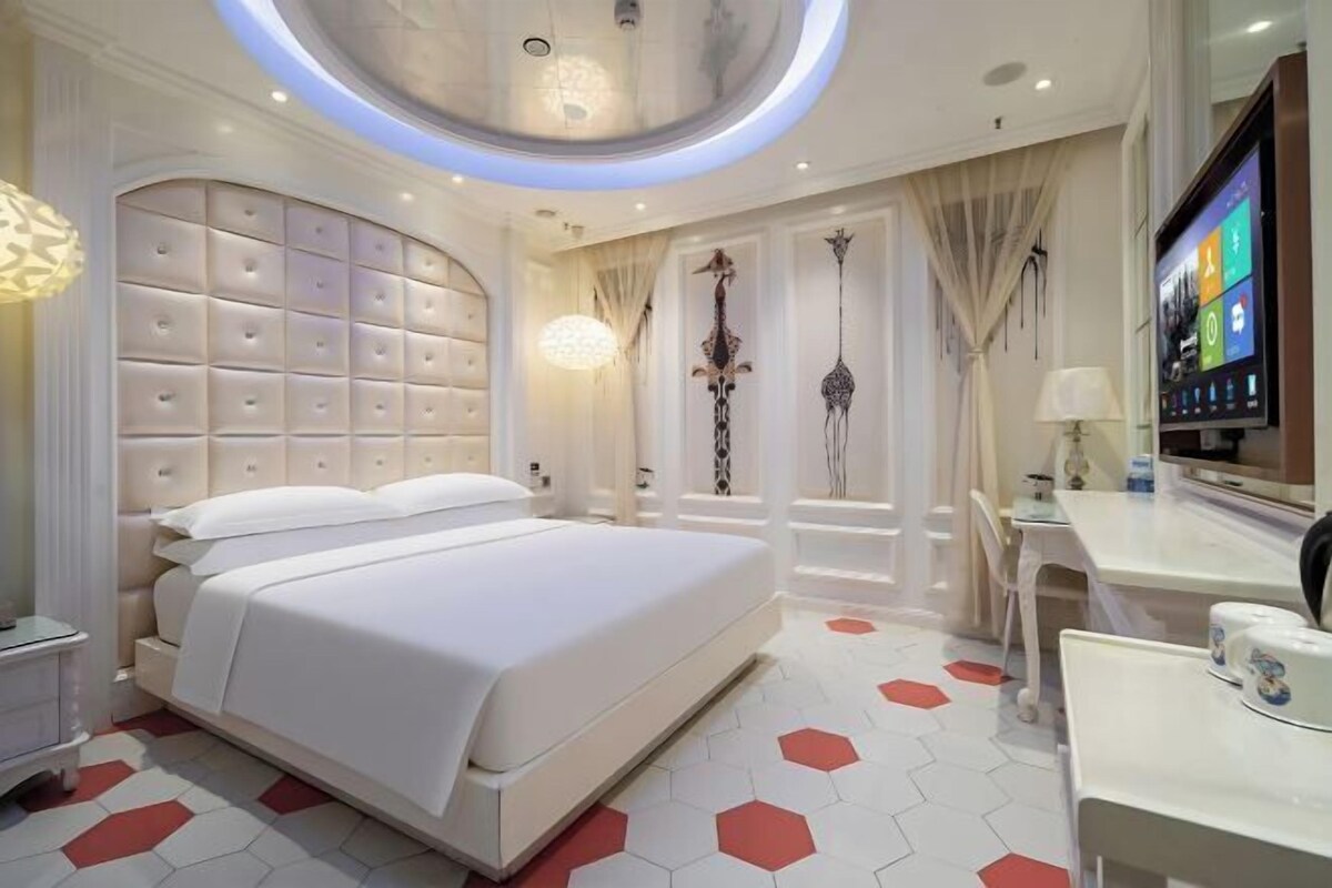A modern hotel room with a large bed, a desk, and a television.
