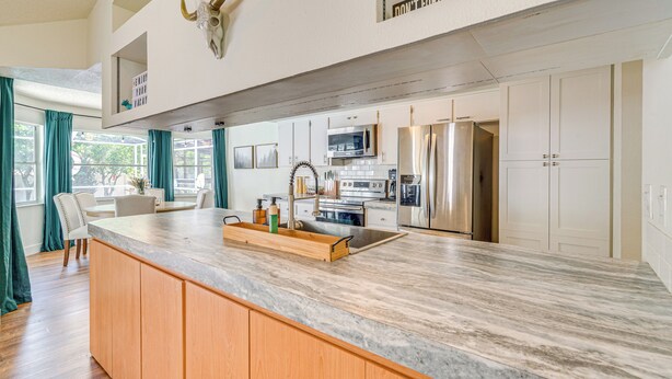 A modern kitchen with a large island, stainless steel appliances, and a bull skull decoration. - Private Pool & Lanai: Spring Hill Oasis (Spring Hill)