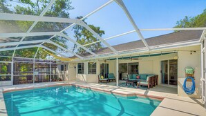 A covered swimming pool with a patio area, chairs, and a ceiling fan. - Private Pool & Lanai: Spring Hill Oasis (Spring Hill)