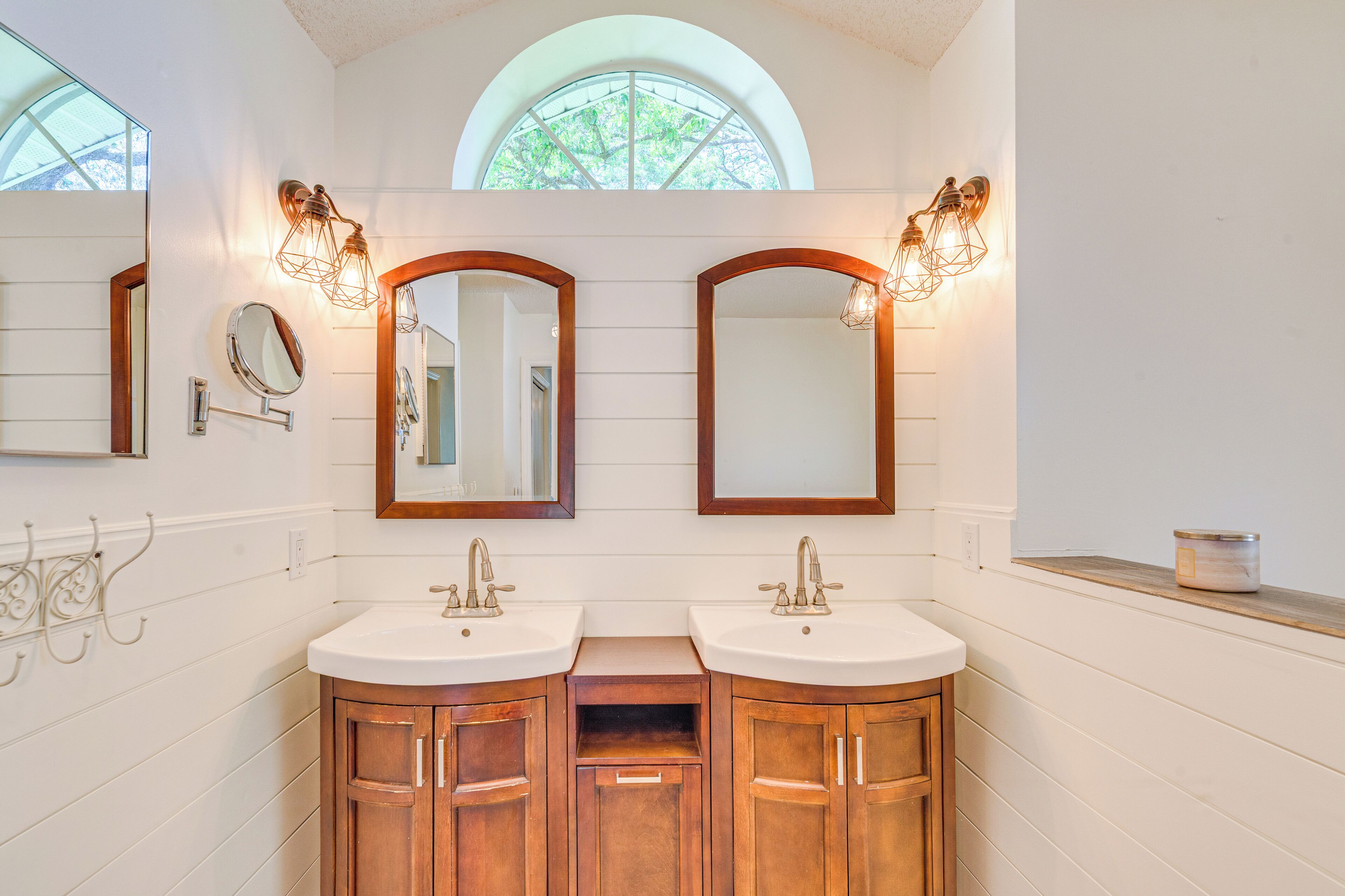A bathroom with two sinks, wooden cabinets, and wall-mounted mirrors.