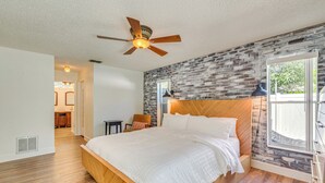 A bedroom with a wooden bed, a ceiling fan, a brick-patterned wall, and a window with a view. - Private Pool & Lanai: Spring Hill Oasis (Spring Hill)
