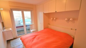A bedroom with a bed, a window, a chair, and a small table. - Apartment in Seaside Bruges With Balcony (Knokke-Heist)