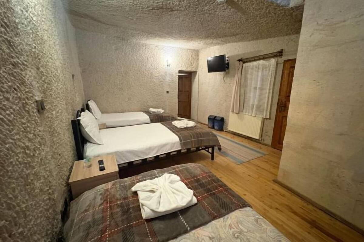 Un dormitorio con dos camas, televisión y ventana con cortinas.