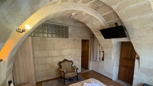 A room with a bed, a chair, and a TV mounted on the wall. - Ekoton Cave Hotel (Nevsehir)