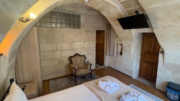 A room with a bed, a chair, and a TV mounted on the wall.
