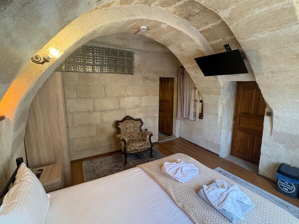 A room with a bed, a chair, and a TV mounted on the wall. - Ekoton Cave Hotel (Nevsehir)