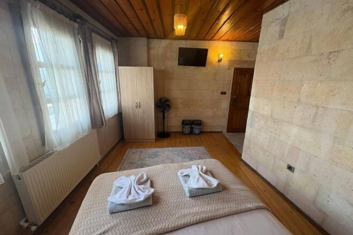 Una habitación con cama, armario, televisor y pared de piedra.