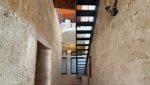 A narrow hallway with textured walls, a patterned rug, a ceiling light, and a view of a room with a closed door and a radiator. - Ekoton Cave Hotel (Nevsehir)