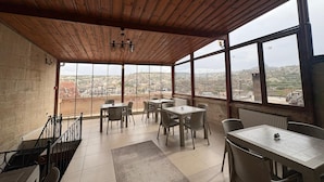 A covered terrace with wooden ceiling and large windows offering a city view. - Ekoton Cave Hotel (Nevsehir)