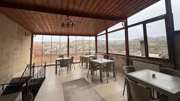 A covered terrace with wooden ceiling and large windows offering a city view. - Ekoton Cave Hotel (Nevsehir)