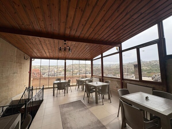 A covered terrace with wooden ceiling and large windows offering a city view. - Ekoton Cave Hotel (Nevsehir)