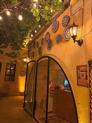 Un espacio exterior con puerta de cristal, placas decorativas en la pared y luces colgantes.