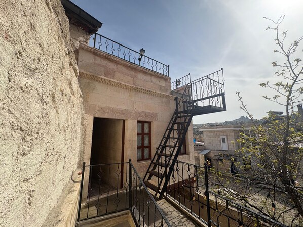 A building with a stone facade, a metal staircase, and a small balcony. - Ekoton Cave Hotel (Nevsehir)