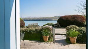 Un patio con vistas a un lago, bancos y plantas en macetas.