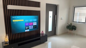 Moderni olohuone, jossa seinälle on asennettu litteänäyttöinen televisio ja seinää koristavat puupaneelit.