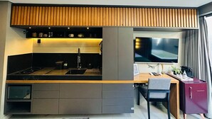 A modern kitchen with a built-in stove, sink, and wooden panel ceiling. There is a dining area with a table and chairs, and a TV mounted on the wall. - Get One (Joao Pessoa)