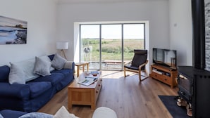 Una sala moderna con un sofá azul, una mesa de centro de madera, un mueble para televisor y una chimenea.