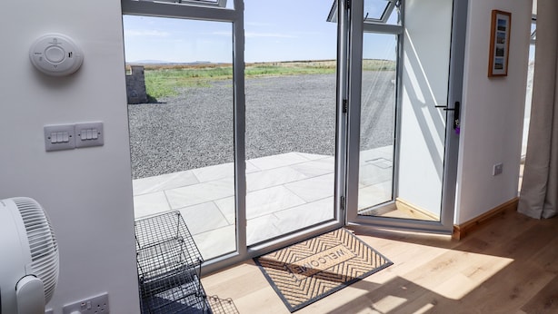 Una habitación moderna con un amplio ventanal corredera que da a un espacio exterior con un sendero de grava y vegetación.