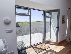 Quarto moderno com uma grande porta de vidro deslizante que dá para uma área externa com caminho de cascalho e vegetação.