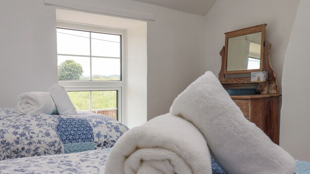A bedroom with a large window, a wooden dresser, and a mirror. - 2 Beck Houses (Malton)