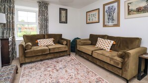 A living room with two sofas, a patterned rug, and framed artwork on the walls. - 2 Beck Houses (Malton)