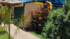 A bus parked in a residential area with a small garden and a white tent. - cabañas puertas del sol (La Rioja)