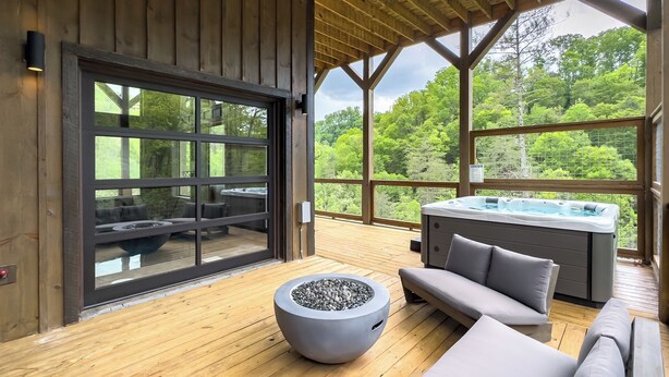 A wooden deck with a hot tub, outdoor seating, and a fire pit. - Pinecone Paradise! Lux~Private~Cave Pool~Fire pit~Game Room~Mountain Setting (Sevierville)