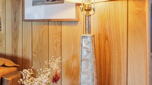 Een houten wand met een ingelijst beeld, een tafel met een lamp en een vaas met bloemen.