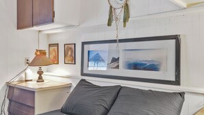 Een slaapkamer met een bed, een nachtkastje, een lamp, een dromenvanger en ingelijste foto's aan de muur.
