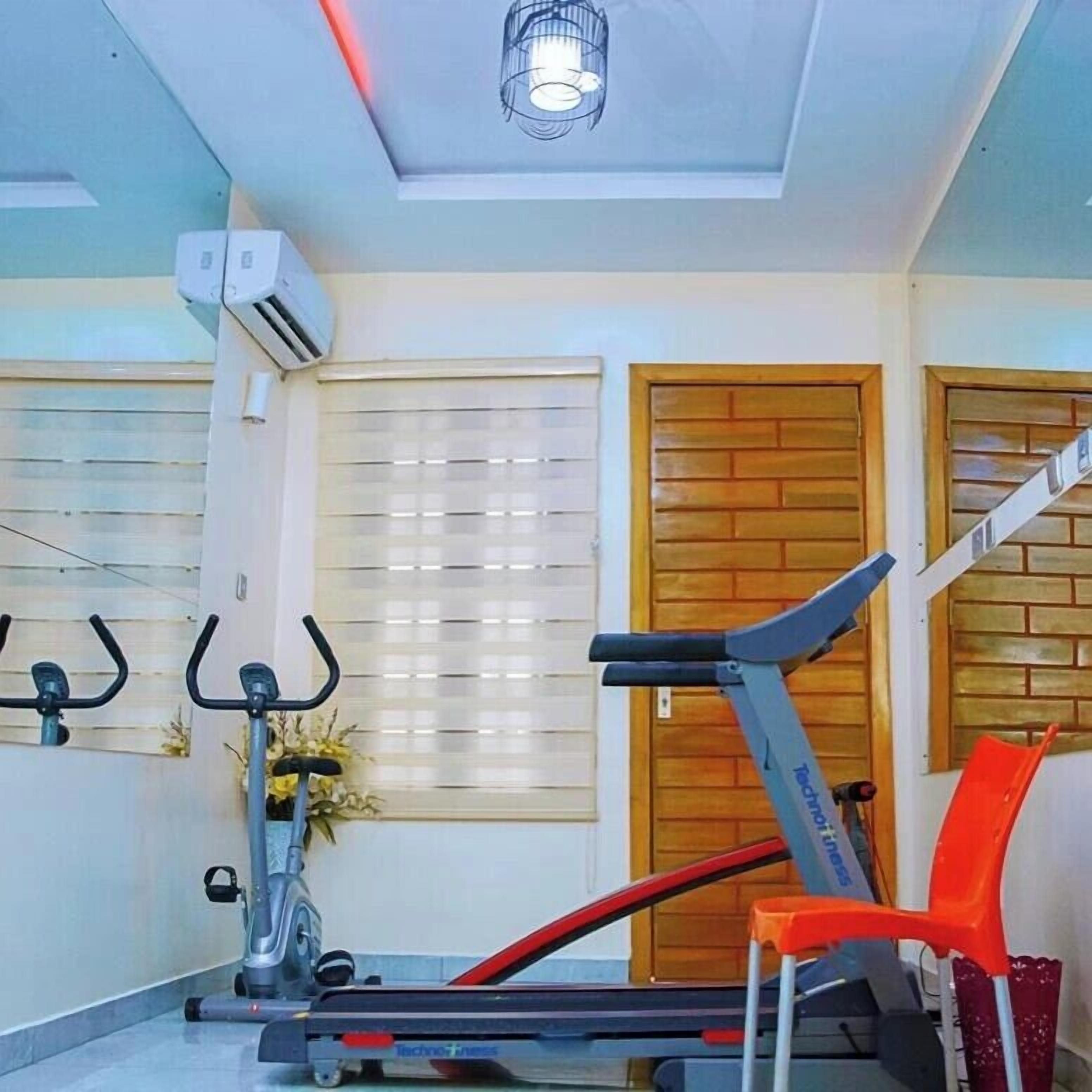 A home gym with a treadmill, stationary bikes, and a red chair.