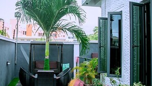 Un edificio moderno con una palmera grande en el centro, una puerta de vidrio y un pequeño espacio de estar al aire libre.