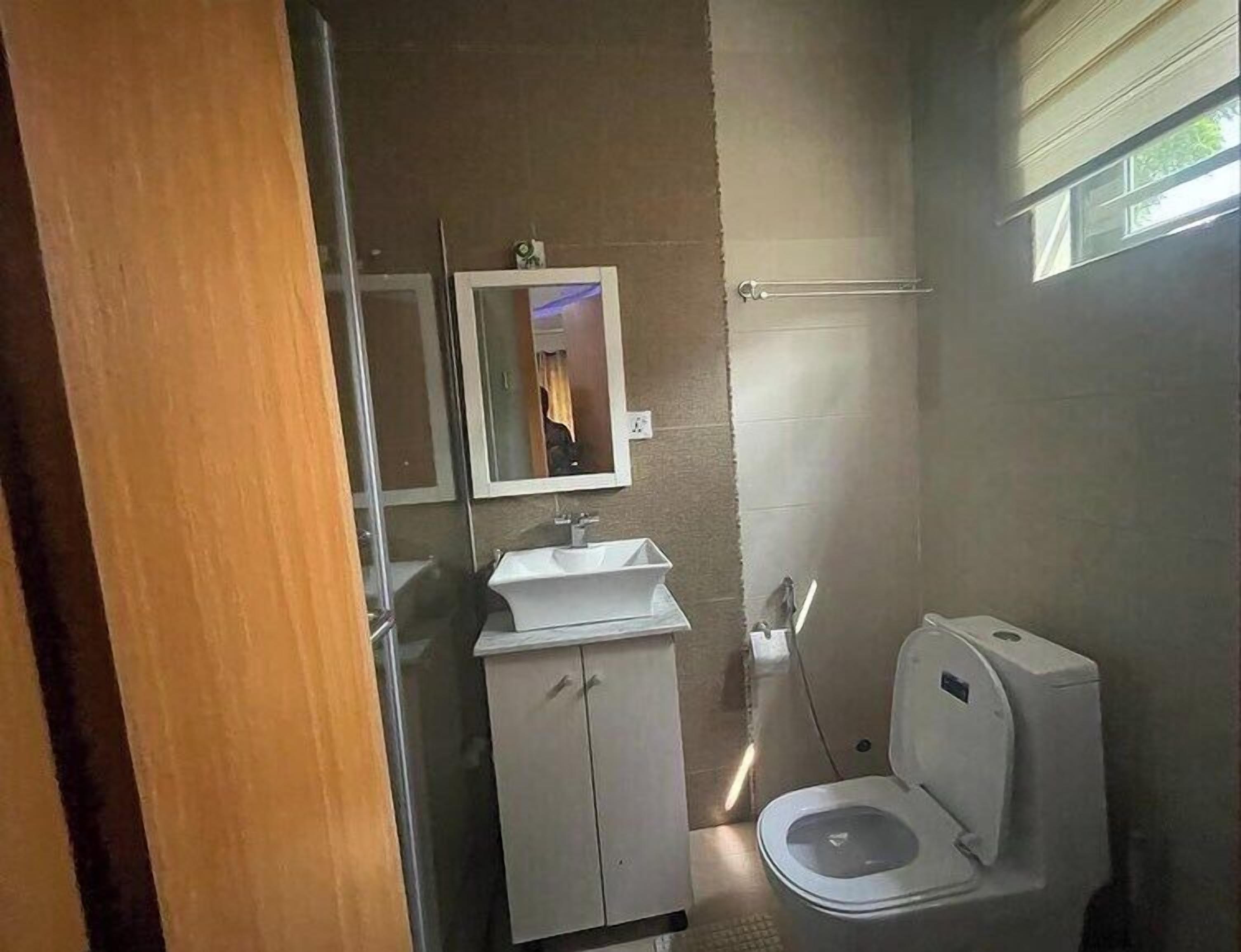 A bathroom with a toilet, a sink, and a mirror.