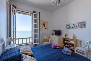 Une chambre avec un grand lit, une chaise, un téléviseur et une bibliothèque.