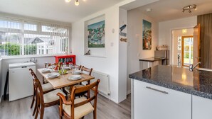 A modern kitchen with a dining area, white cabinetry, and a view of the outside. - 3 bedroom accommodation in Lamlash (Lamlash)